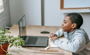 Przygotowanie do egzaminu ósmoklasisty online i stacjonarnie w lubelskim – jakie opcje są dostępne? Uczeń szkoły podstawowej siedzi przy biurku i uczestniczy w zajęciach online na laptopie, obok leży zeszyt do notatek, ołówek i linijka. Chłopiec skupia się na ekranie podczas lekcji, co dobrze oddaje ideę kursów dla ósmoklasistów online Symposio przygotowujących do egzaminu ósmoklasisty – więcej informacji można znaleźć na stronie organizatora